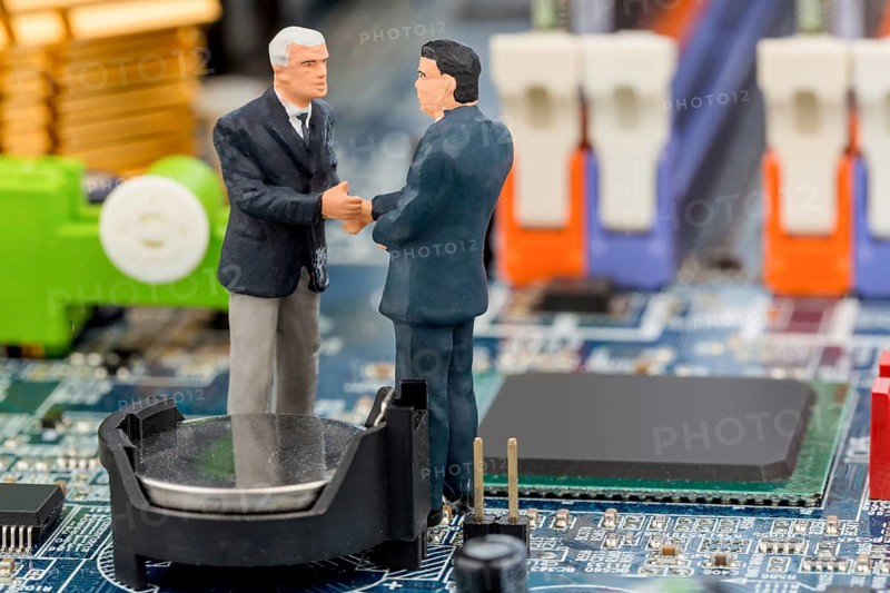 Two managers are having a conversation standing on the circuit board of a computer