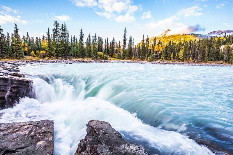 The full-water bubbling waterfall of Athabasca. Clear autumn evening in Canada. Cold blue water at sunset. The concept of extreme and ecological tourism