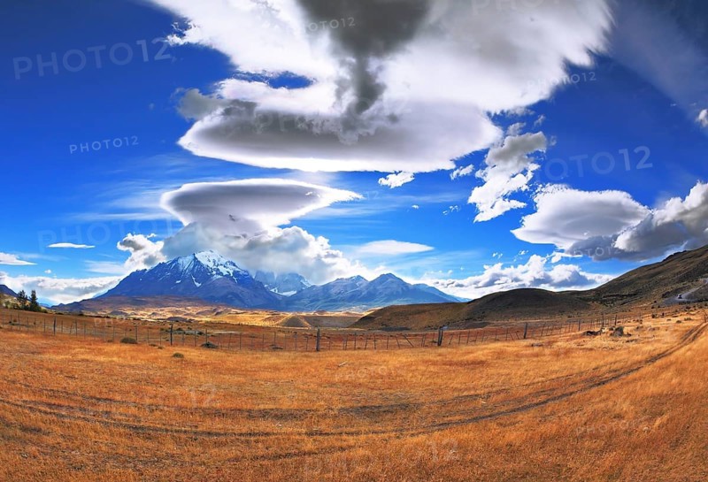 The Chile National Park Torres del Paine. Incredible shaped clouds formed by glaciers glisten in the sun. On the horizon are seen mountains with snow-capped peaks. Picture taken with a fisheye lens