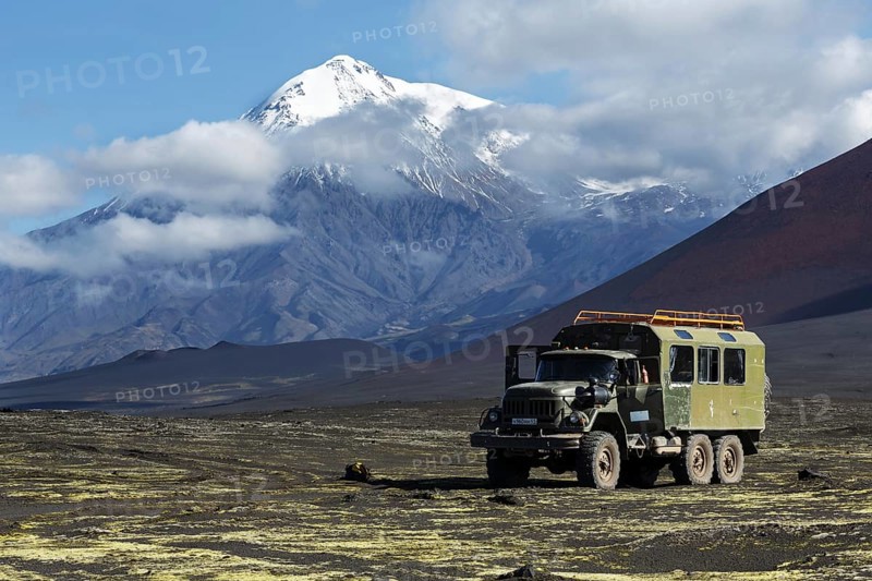 TOLBACHIK VOLCANO, KAMCHATKA, RUSSIA, AUG 27, 2014: Russian off-road extreme expedition truck ZIL-131 (6-wheel drive) on mountain road on volcanic slag field on background of beautiful volcano. Russia, Kamchatka, Klyuchevskaya Group of Volcanoes