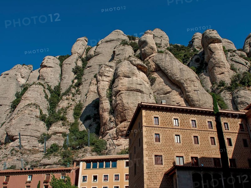 Building at the foot of rocky mountains under a clear sky in Montserrat, montserrat, spain