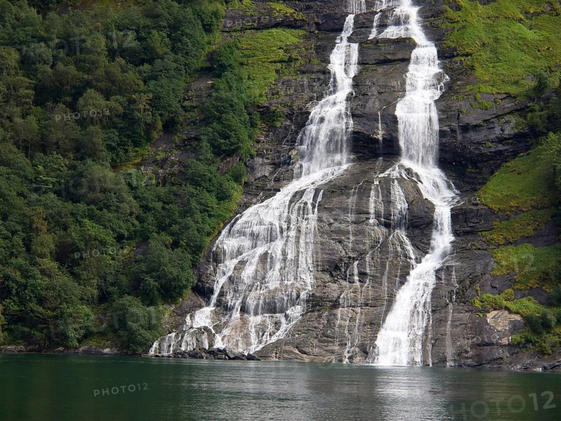 Close-up of a waterfall over green rocks with dense forest, Molde, Norway