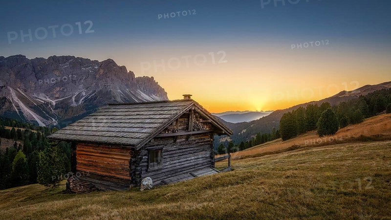 Passo Erbe under the mountain Peitlerkofel, or Sass de Putia in the light of the setting sun with wood hut