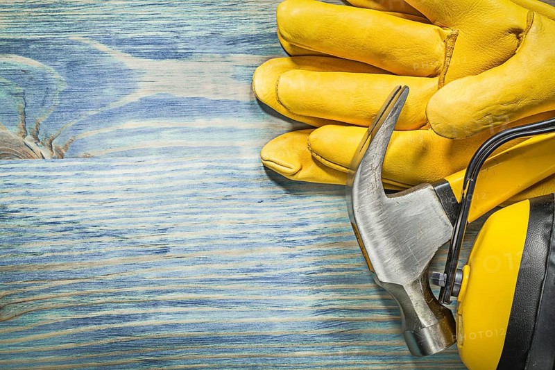 Composition of protective workwear claw hammer on wood board construction concept