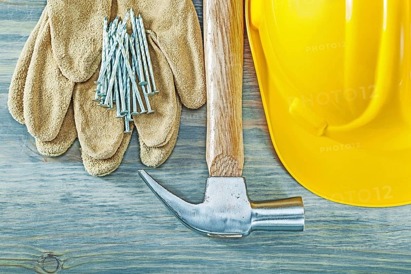 Hard hat protective gloves claw hammer nails on wooden board construction concept