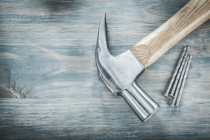 Claw hammer nails on vintage wooden board construction concept