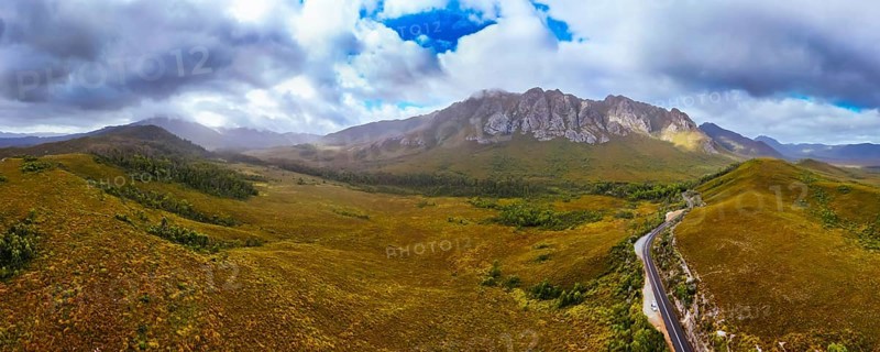 An aerial view of Gordon River Rd at the Sentinel range of mountains near Bitumen Bones Sculpture on a hot summer's afternoon in Southwest National Park, Tasmania, Australia