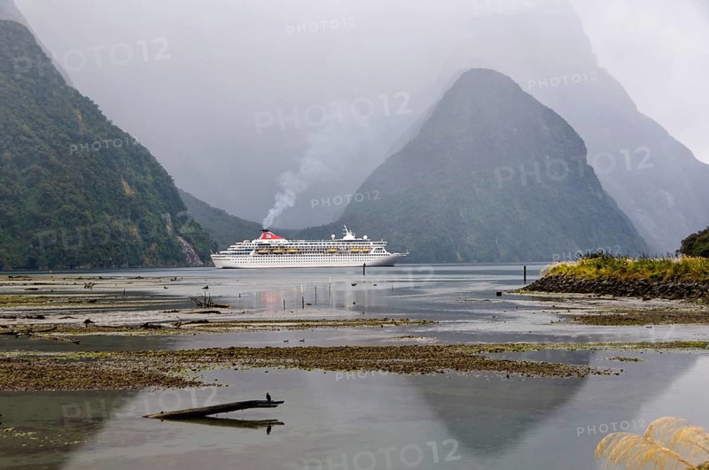 Cruise ship in the evening of an overcast day in the majestic Milford Sound on the South Island of New Zealand