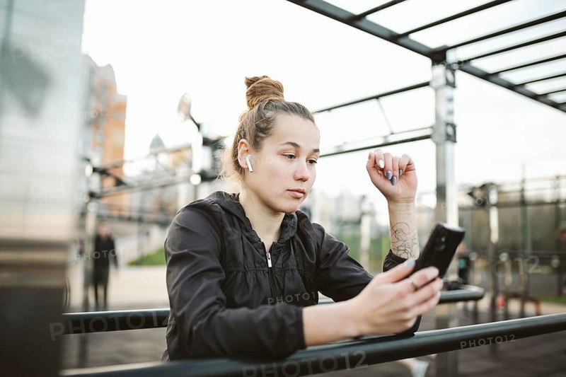 Sportswoman listening to music using phone app for fitness activity tracker heart rate monitor tracking health progress on smartphone. Sports and healthy. Caucasian young sporty woman in headphones