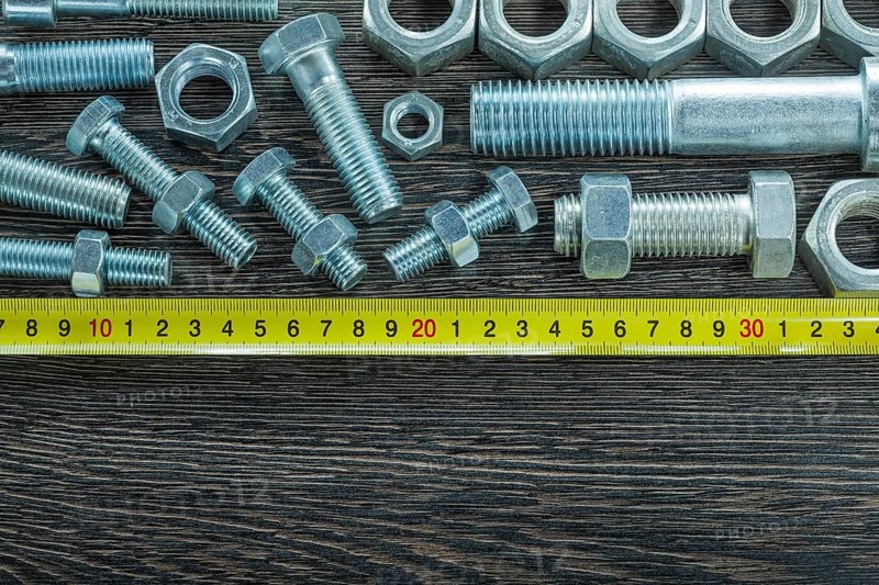 Bolts nuts tape measure on wooden board