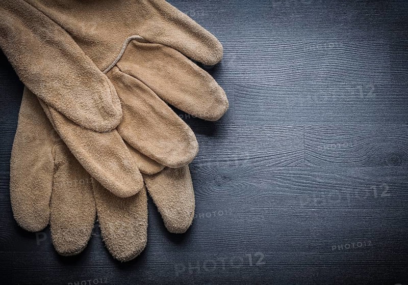 Two working leather gloves on dark wood board