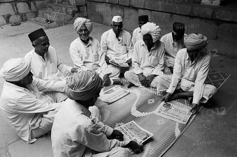 Rural people seating in group and reading news papers, Munagoli village, Bijapur district, Karnataka, India