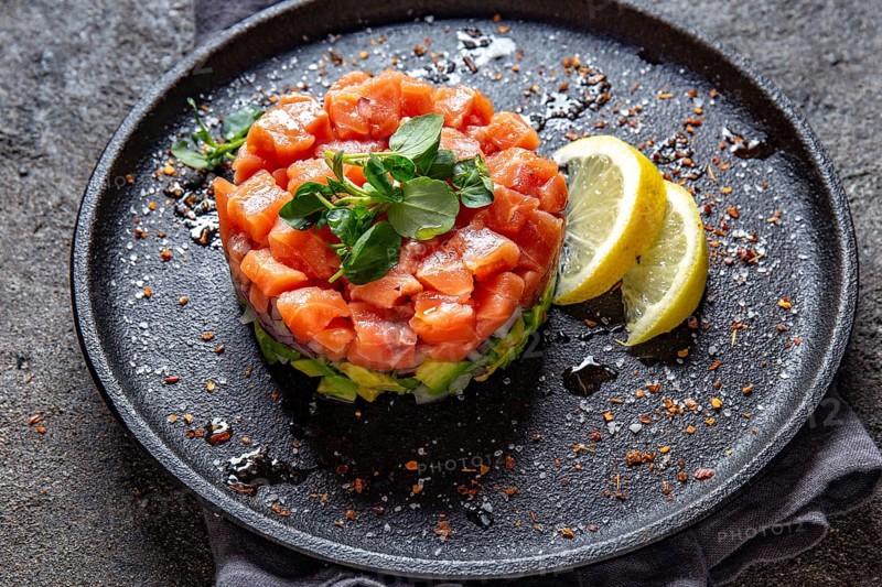Food, Raw salmon, avocado purple onion salad served in culinary ring on black plate. Black concrete background