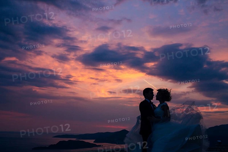 Silhouette of the newlyweds against the sky at sunset. Wedding in Montenegro. Silhouette of a couple. Silhouette of the bride and groom