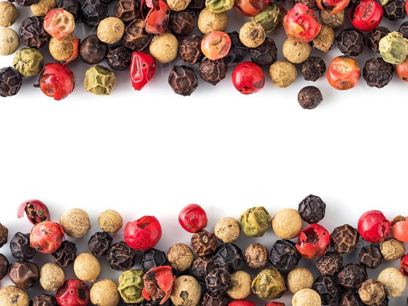 Mixed peppercorns background with white copy space in center. Food background with peppercorns. Different colored peppercorns pattern on white background, top view or flat lay