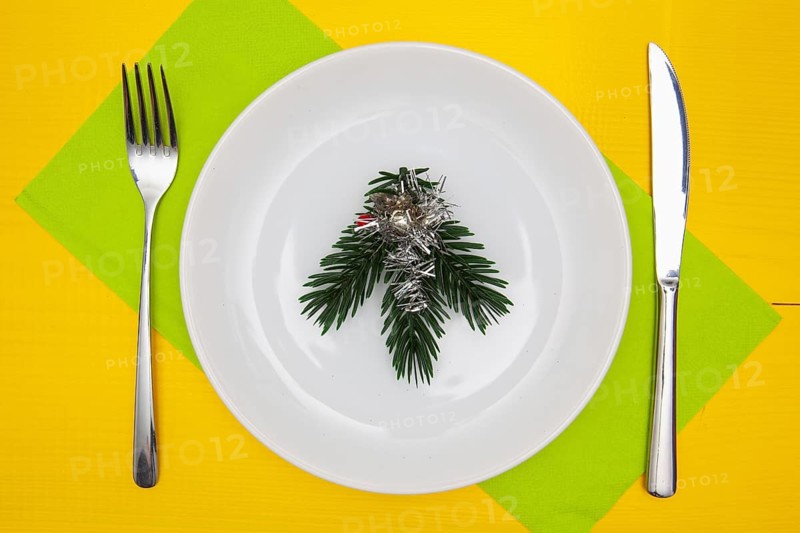 White plate and green Christmas decoration on the yellow wooden table.Top view.Flat Lay Image