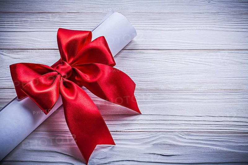 Roll of paper with red bow on wooden board holidays concept