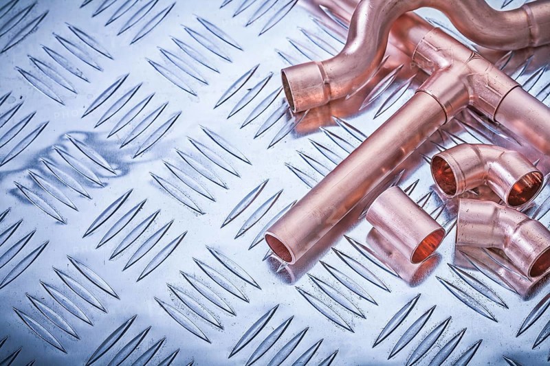 Copper pipe fittings on grooved metal plate plumbing concept