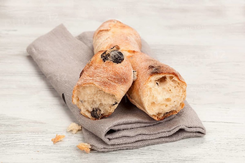 Delicious pastry on wooden table. Olive baguette