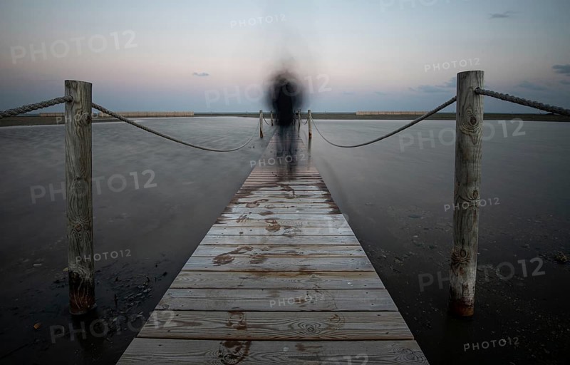 An unrecognised person walking like a ghost at a wooden pier