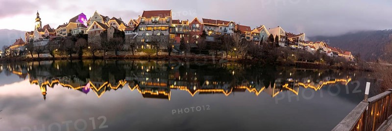 Christmas illuminated house facade of Frohnleiten reflected in the river Mur, panoramic view, Frohnleiten, Styria, Austria