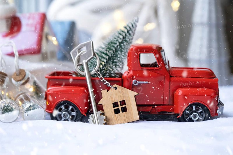 Red retro car with a Christmas tree decorates with the house key in the pickup truck for Christmas. Buying a home, moving, mortgage, loan, real estate, festive mood, New Year