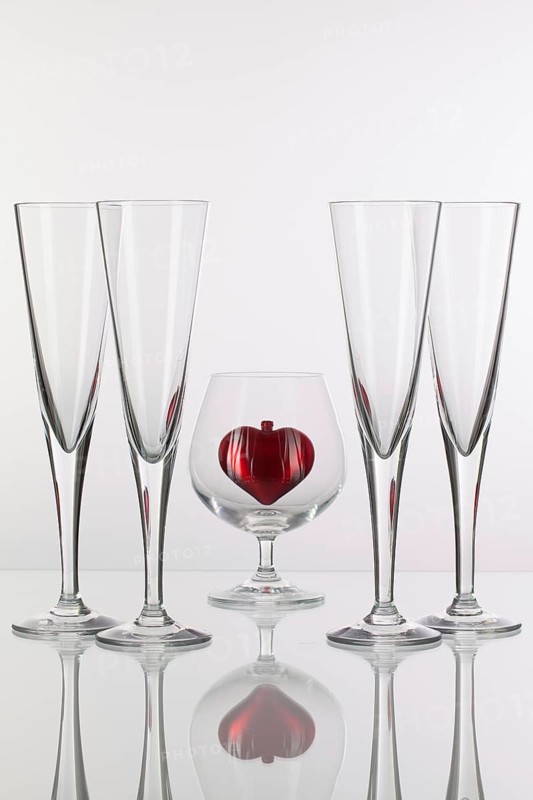 Different glasses and red heart on a glass plate