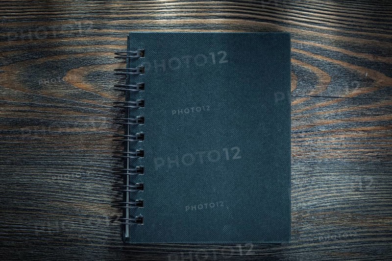 Black spiral notebook on vintage wooden board