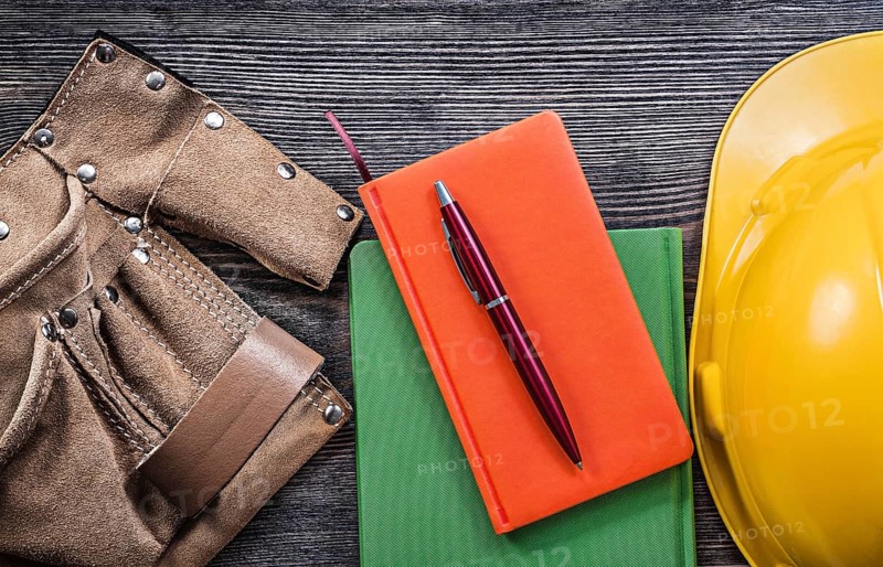 Set of tool belt note-books pen hard hat on wooden board construction concept