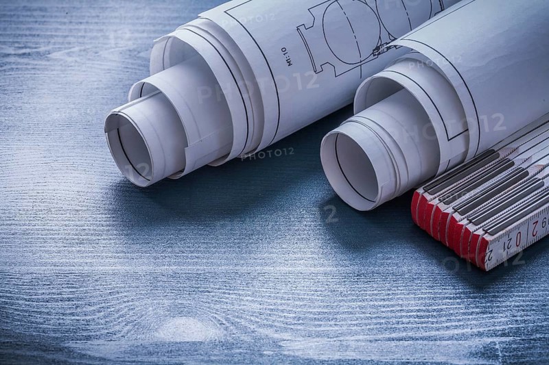 Two rolls of blueprints and white wooden meter