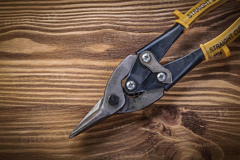 Tin snips on vintage wooden board top view construction concept