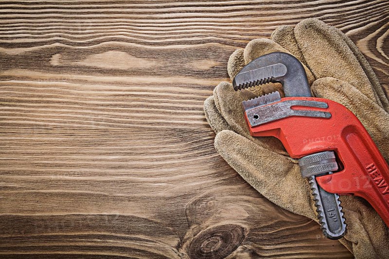 Pair of leather protective gloves monkey wrench on wood board construction concept