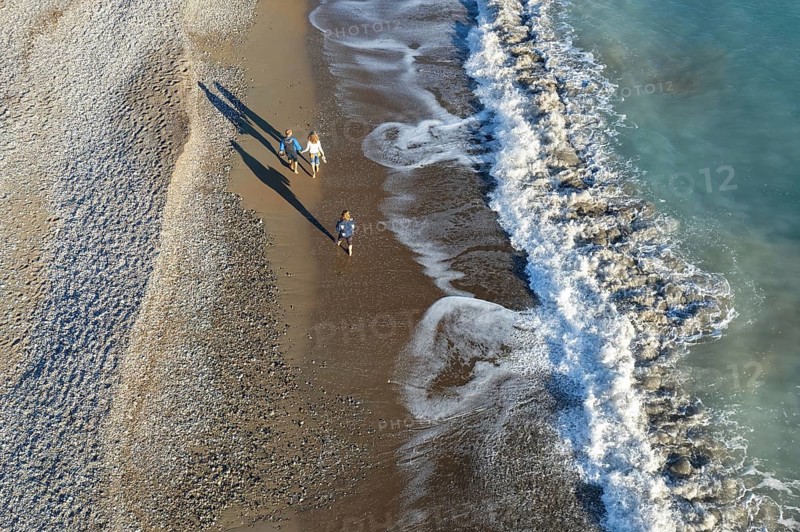 Aerial drone point of view of person walking on sand in a beach. Stormy waves idyllic beach in winter