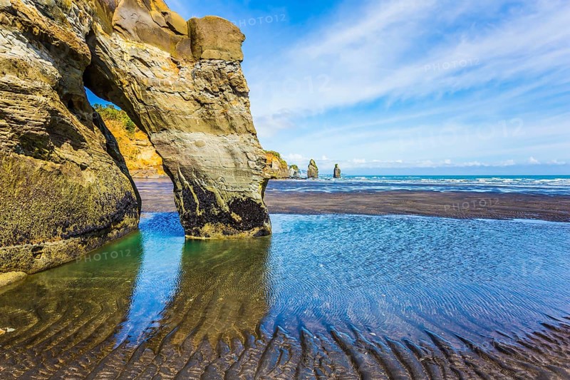 Coastal rock arches Three Sisters and Elephant on the Pacific coast. The concept of active and phototourism. New Zealand, North Island