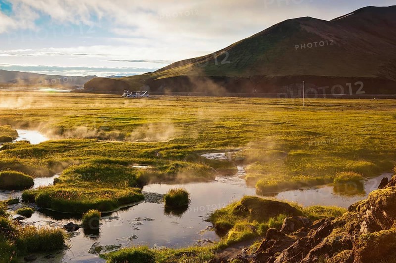 Above the source of thermal water steam rises. White nights in Iceland. Sunrise Park Landmannalaugar