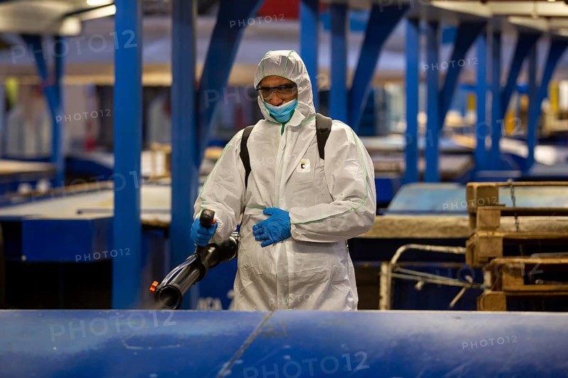Sofia, Bulgaria - 7 April, 2020: Worker sprays disinfectant outside of ? food market against the spread of coronavirus disease COVID-19