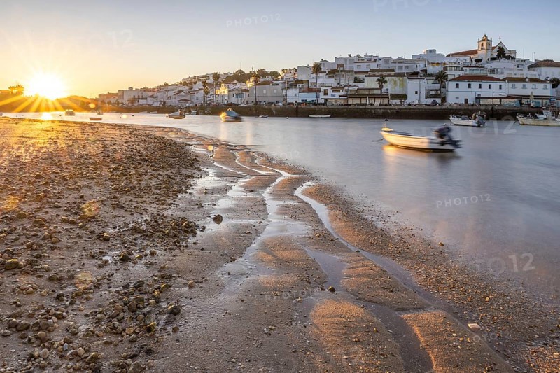 Sunrise with view over a beach and harbour basin at low tide. Panorama picture of a historic old town in the morning, of the village Ferragudo, Portimão, Algarve, Portugal