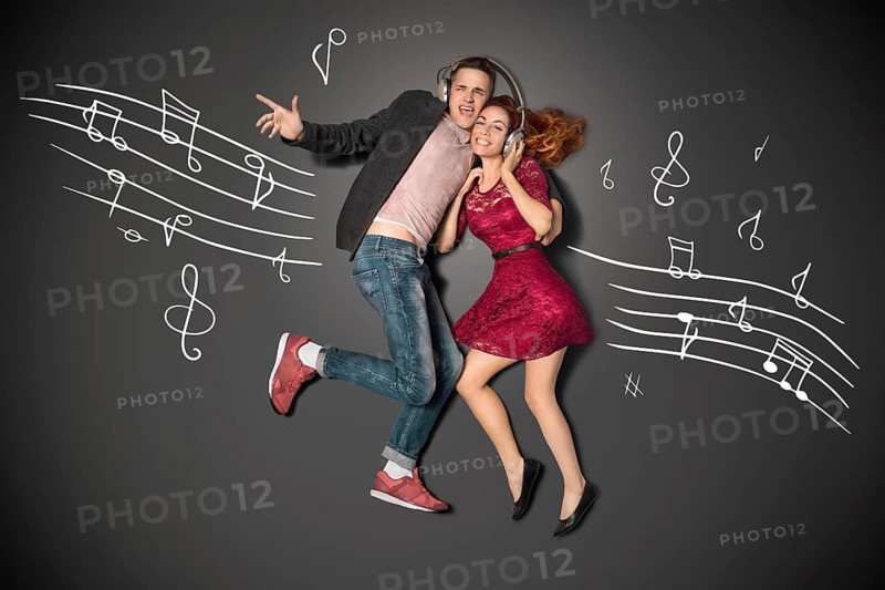 Happy valentines love story concept of a romantic couple sharing headphones and listening to music against chalk drawings background