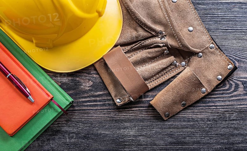 Leather tool belt notepads pen protective building helmet on wooden board construction concept
