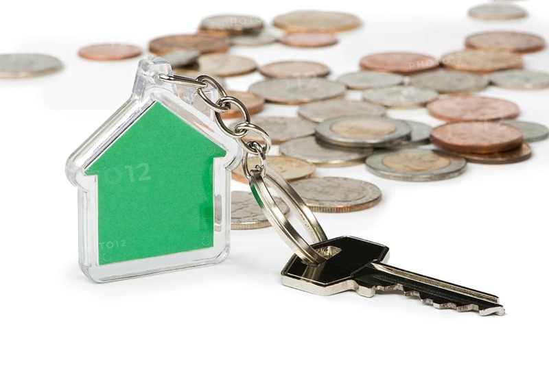 Coins and green house key ring. White isolated studio shot