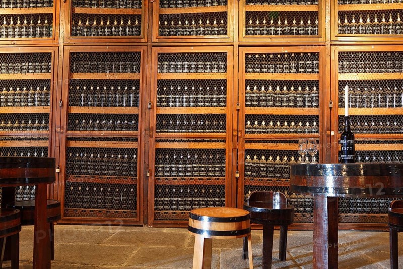 FUNCHAL, MADEIRA - OCTOBER 08, 2011: Museum - repository of expensive vintage wine Madera. Long rows of shelves made of bottles of wine. In the aisle is a round table and stools