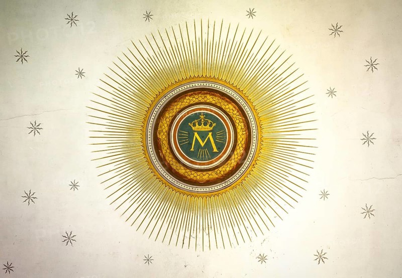 Monogram of the Blessed Virgin Mary, with crown, sun and stars on the background