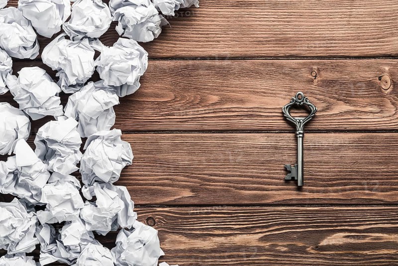 Concept of success and opportunity with old key among paperballs