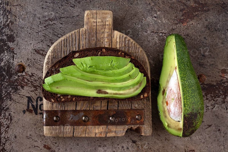 Avocado sandwich on wooden board, vintage iron background