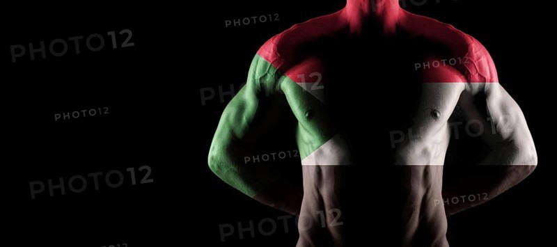 Sudan flag on muscled male torso with abs, black background