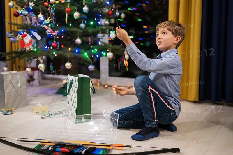Happy boy opening a Christmas gift and Christmas tree in the background