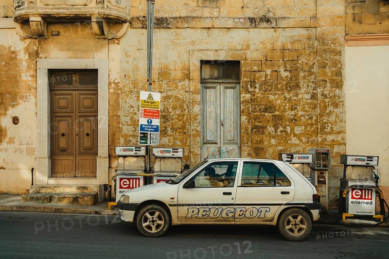 A person refueling a car at a local small gas station located by the side of the road. Self-service refueling. Citadella Gozo, Malta