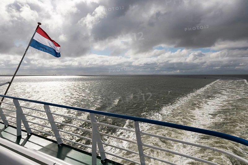 Wadden Sea with Dutch flag and wake as seen from the ferry