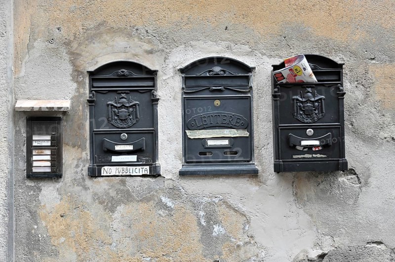Three worn letterboxes on an old, faded wall, Orvieto, Italy