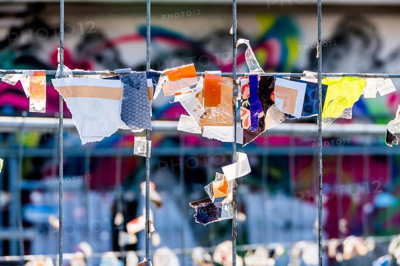 Scraps of paper against a wire fence, symbolising creativity, disorder, protest